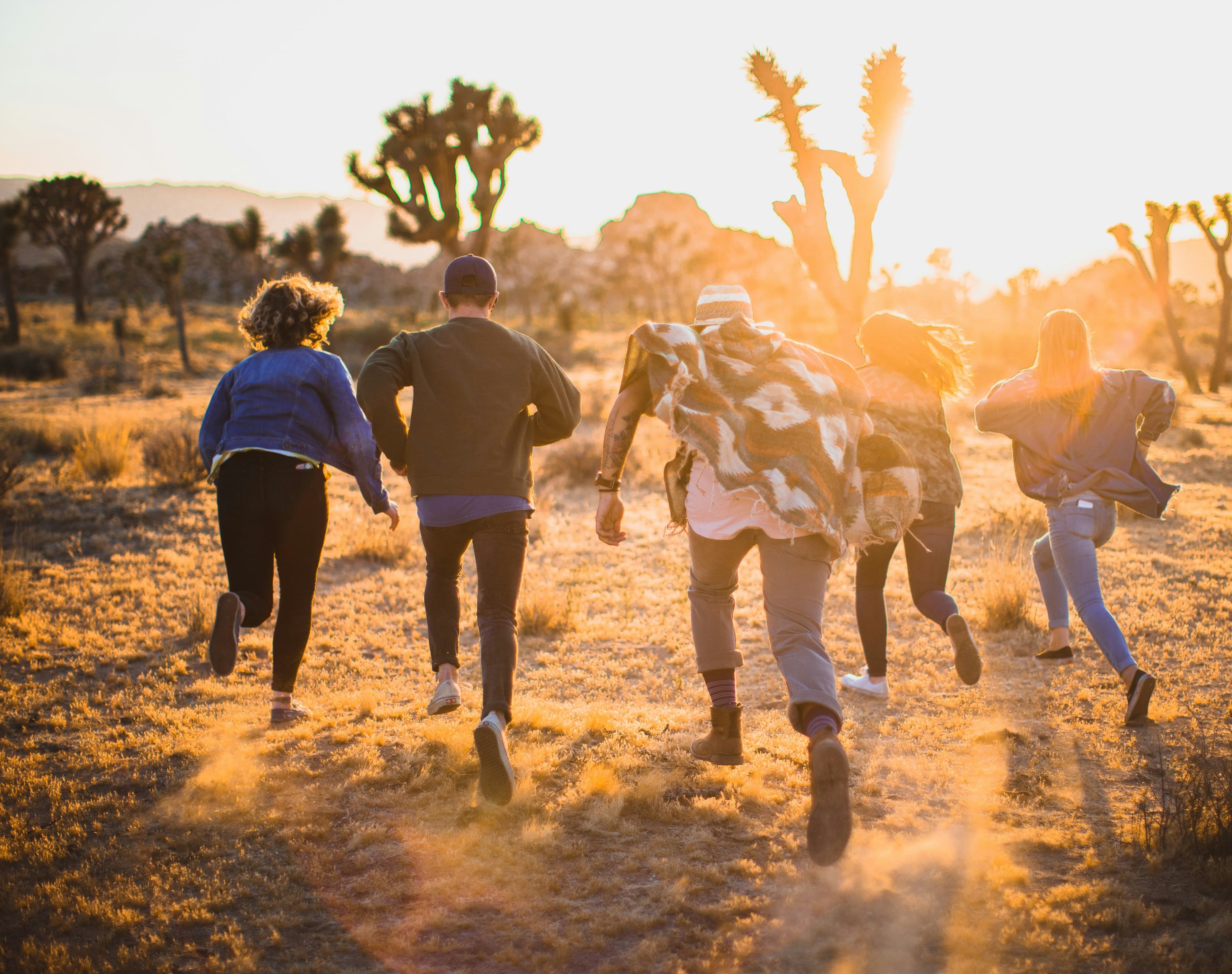 Friends running through a desert landscape at golden hour.